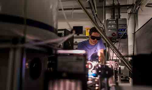 Man in blue t-shirt and protective glasses looking at equipment
